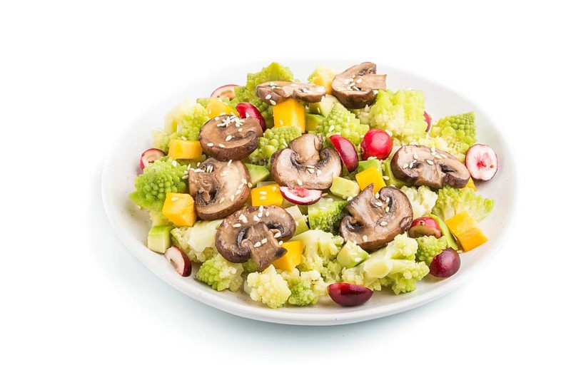 Vegetarian salad from romanesco cabbage, champignons, cranberry, avocado and pumpkin isolated on a white background. side view, close up