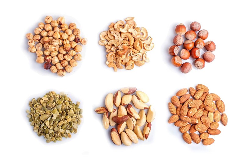 Piles of various nuts and seeds isolated on white background. hazelnut, brazil nut, almond, pumpkin seeds, cashew. top view