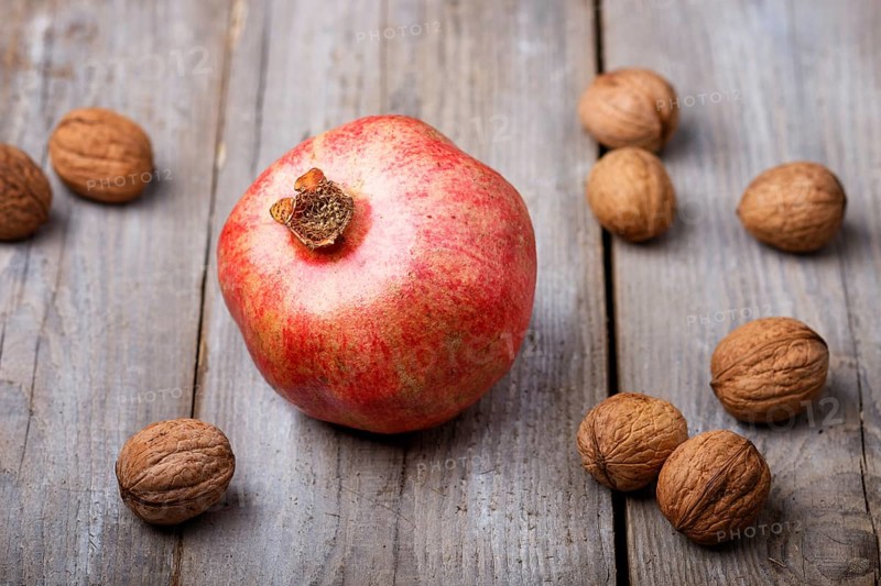 Ripe garnet with walnuts on a rustic wooden background