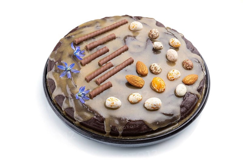 Homemade chocolate brownie cake with caramel cream and almonds isolated on a white background. Side view, close up