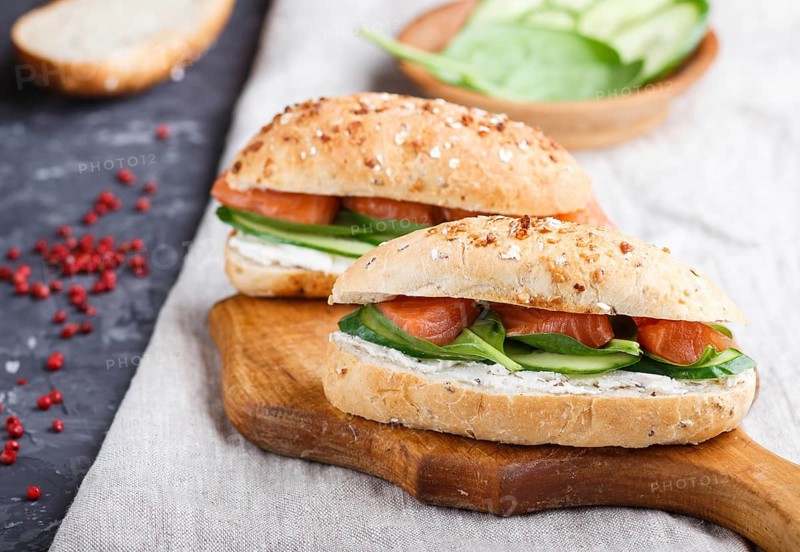 Smoked salmon sandwiches with cucumber and spinach on wooden board on a linen background. side view, close up