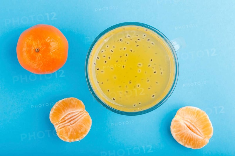 Glass of tangerine orange colored drink with basil seeds on a blue background. Morninig, spring, healthy drink concept. Top view, close up, flat lay