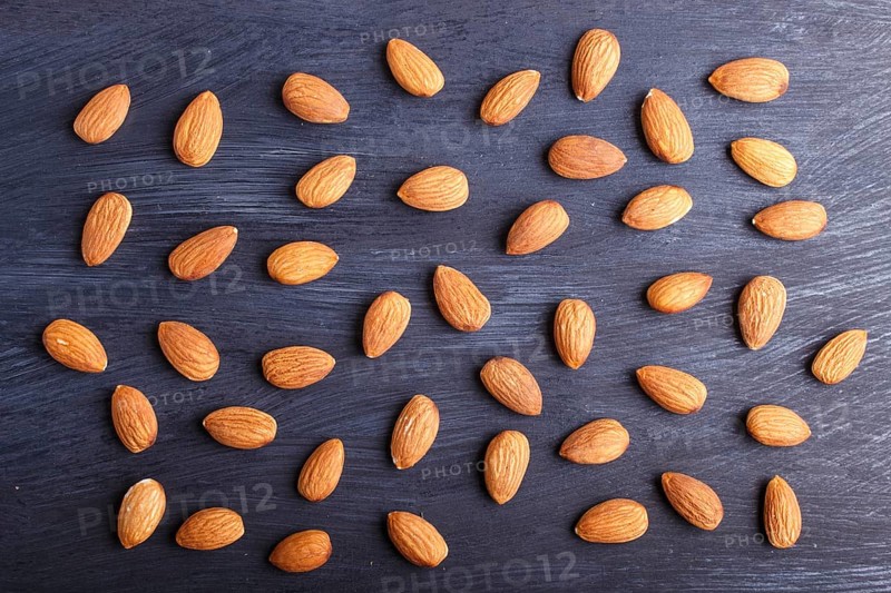Pattern and texture made from almonds on black wooden background, flat lay. top view