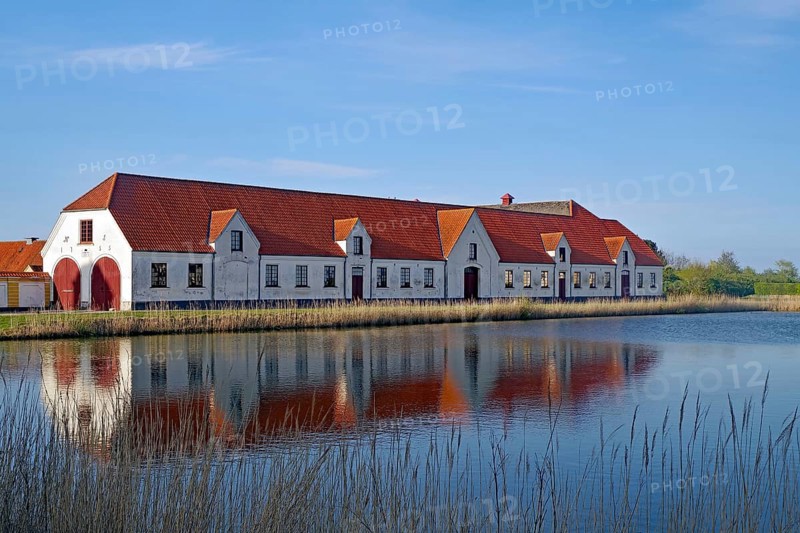 Large houses and the teahouse at Valdemars Slot are reflected in the calm water, Valdemars Slot, Manor Route, Tasinge, Denmark, Europe