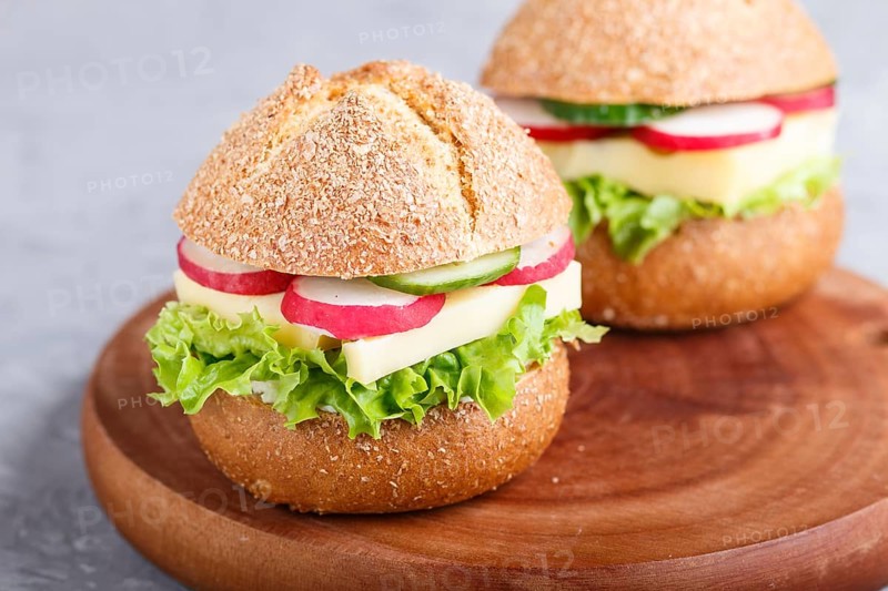 Sandwiches with cheese, radish, lettuce and cucumber on wooden board on a gray concrete background. side view, close up, selective focus