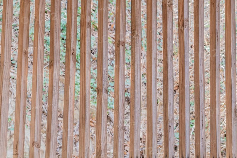 Vertical wooden slats in wall of building with blurred grassy hill in background in South Korea