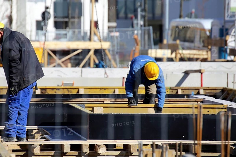 Construction work on the foundations of a large apartment building. The construction workers are wearing construction helmets in accordance with regulations