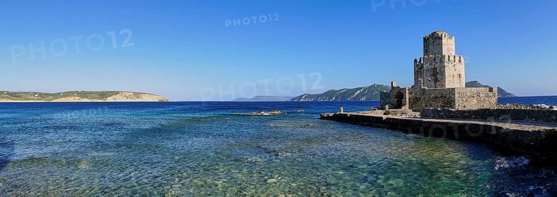 An old stone tower on a coast with crystal clear sea water under a wide blue sky, octagonal medieval tower. Islet of Bourtzi, sea fortress of Methoni, Peloponnese, Greece, Europe