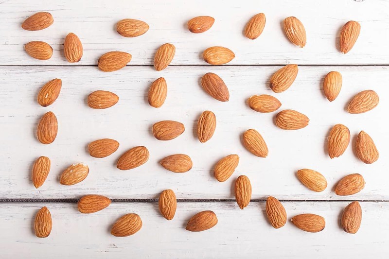 Pattern and texture made from almonds on white wooden background, flat lay. top view