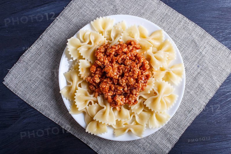 Farfalle bolognese pasta with minced meat on black wooden background. top view, close up