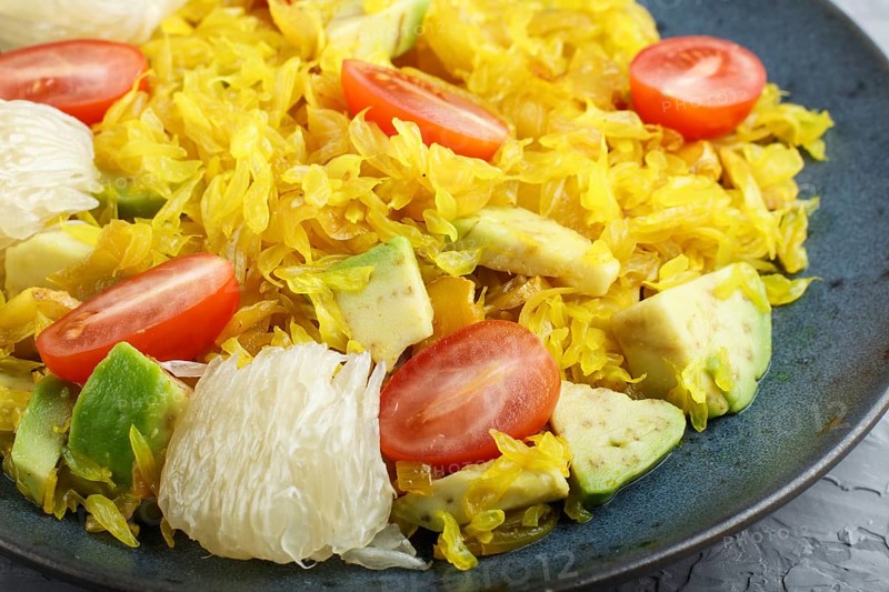 Fried pomelo with tomatoes and avocado on gray concrete background, close up, myanmar food