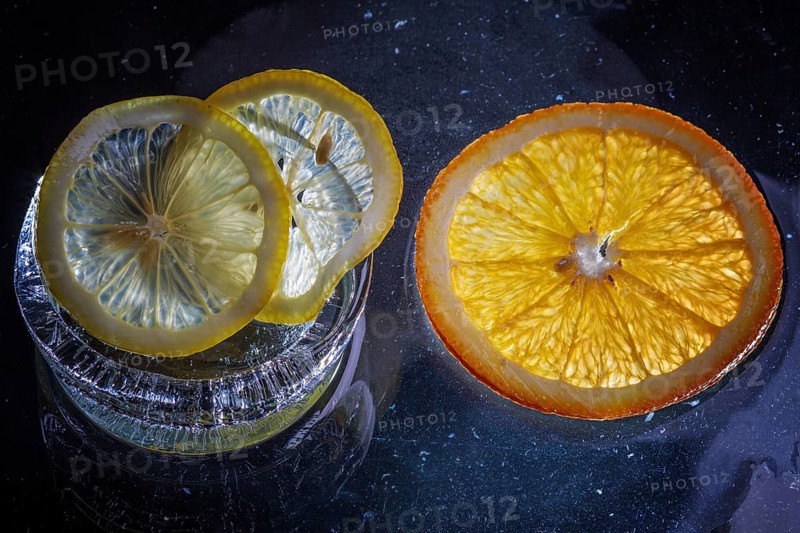 Transparent slices of fresh oranges and lemons on the glass with ice