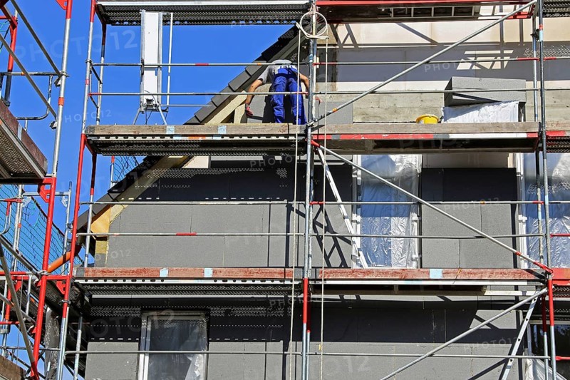 Construction workers insulate a house facade