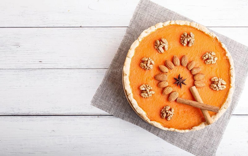 Traditional american sweet pumpkin pie decorated with nuts, on white wooden background. top view, copy space