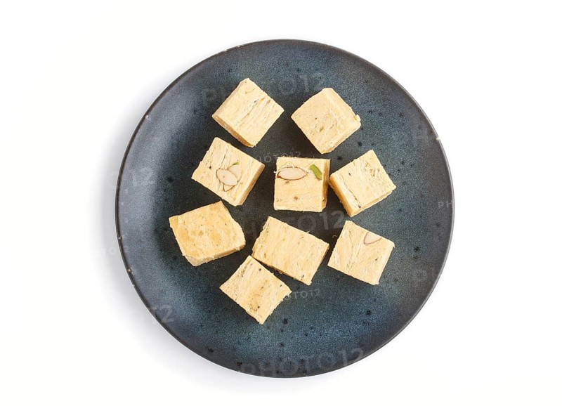 Traditional indian candy soan papdi in blue ceramic plate isolated on a white background. top view, close up, flat lay