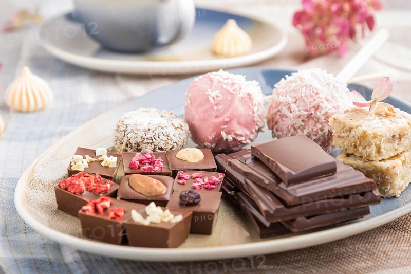 A pieces of homemade chocolate with coconut candies on a blue and brown textile. side view, close up, selective focus
