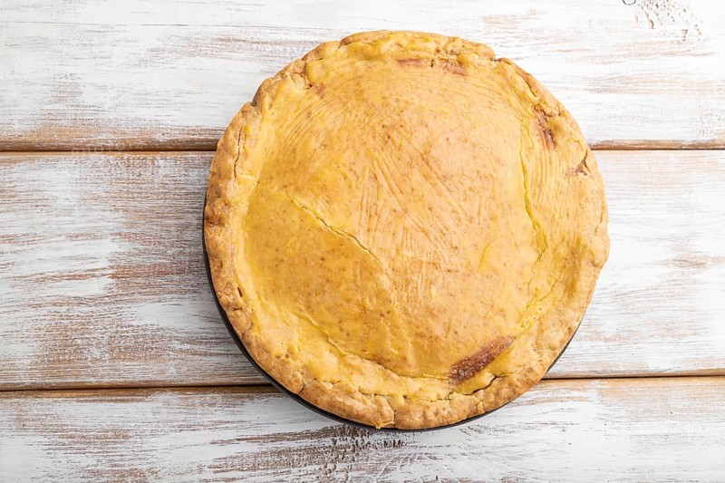 Autumn onion pie and cup of coffee on white wooden background. Top view, flat lay, close up