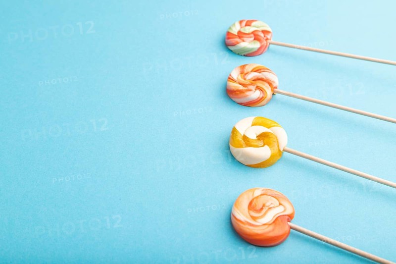 Four lollipop candies on blue pastel background. copy space, side view