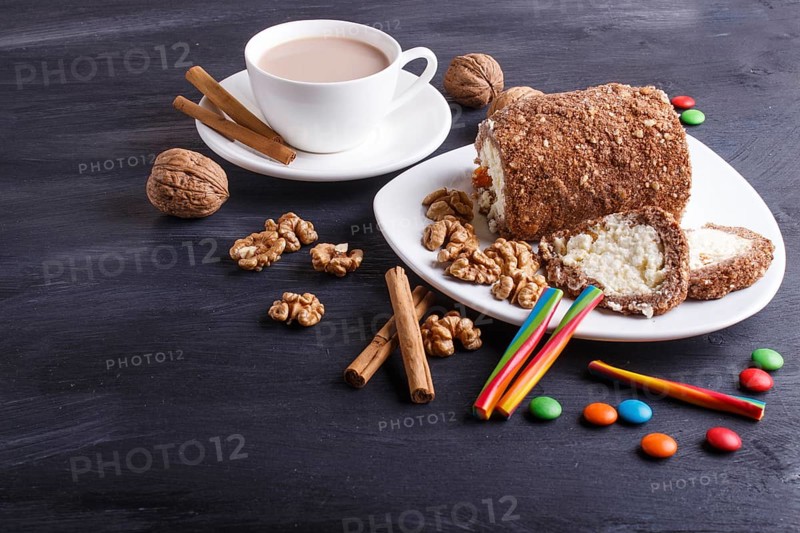 Roll cake with curd and walnuts isolated on black wooden background. close up