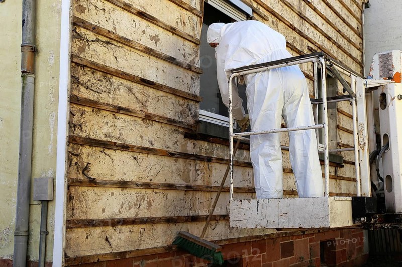 Professional asbestos removal by workers in protective suits