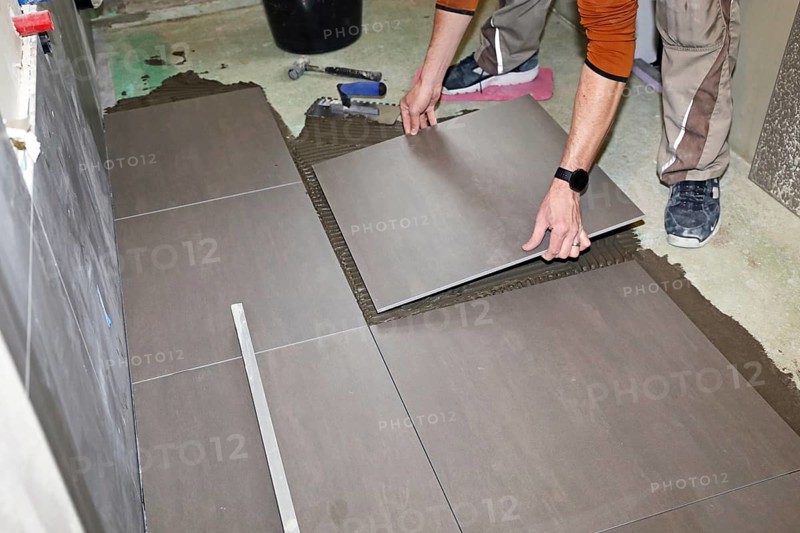 Tiler lays modern large floor tiles in a bathroom