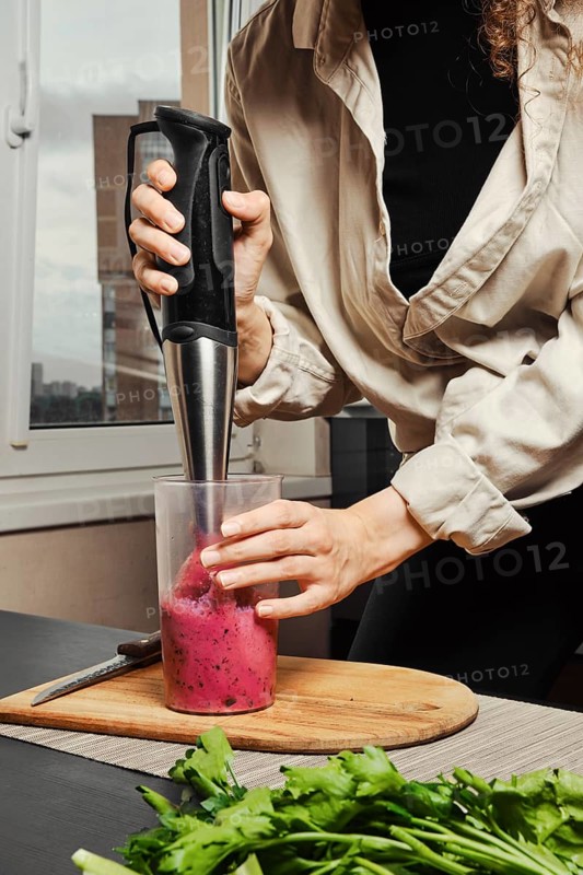 Unrecognizable woman making purple smoothie with banana and black currant
