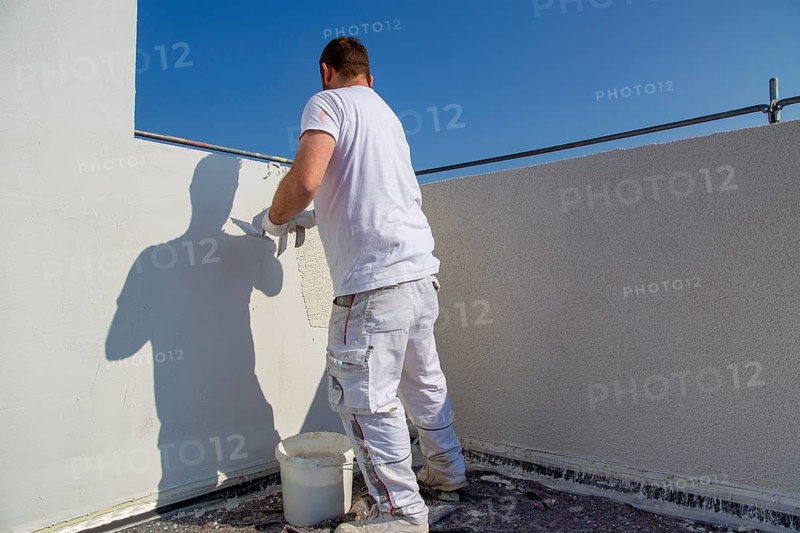 Plasterer plasters the facade of a new building