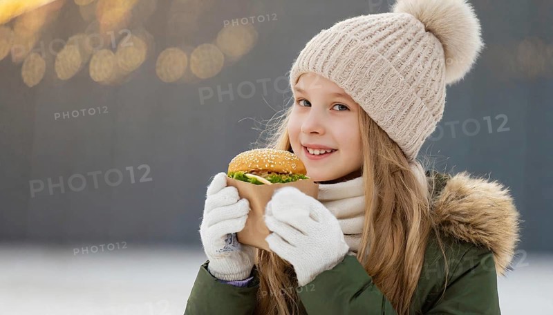 AI generated, human, humans, person, persons, child, children, girl, 10, 12, years, one person, outdoor, ice, snow, winter, seasons, eats, eating, burger, hamburger, cap, bobble hat, gloves, winter jacket, cold, coldness