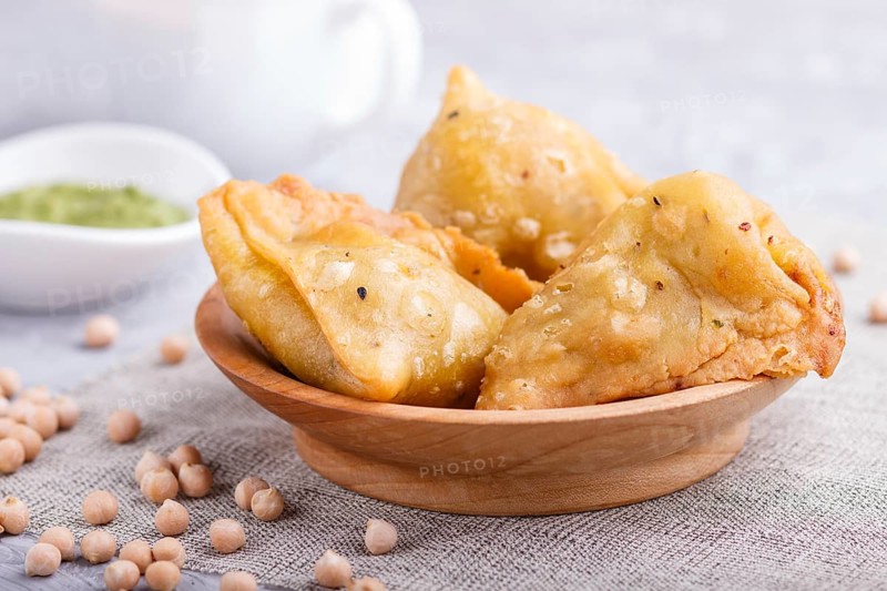 Traditional indian food samosa in wooden plate with mint chutney on a gray concrete background. side view, close up