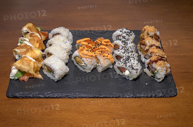 A slate plate hosting a variety of sushi rolls with different toppings and sauces, Majorca, Balearic Islands, Spain, Europe