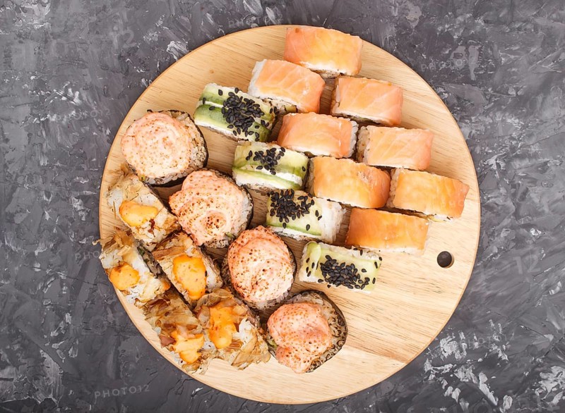 Mixed japanese maki sushi rolls set on black concrete background. Top view, close up, flat lay