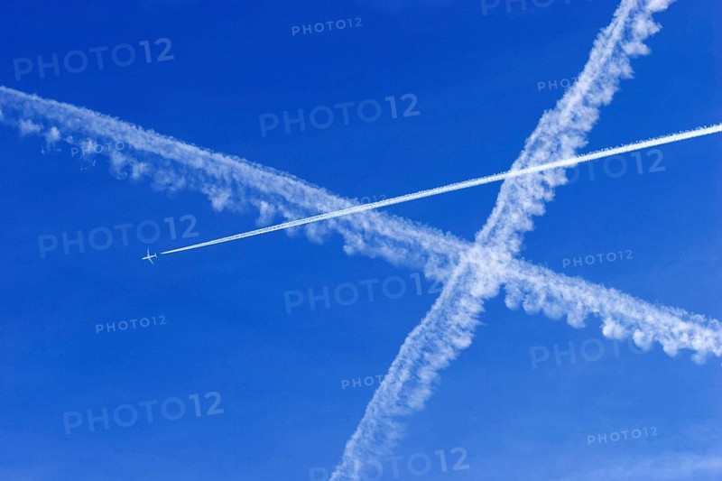 A passenger plane with vapour trails high in the blue sky