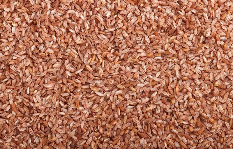 Texture of unpolished brown rice. Top view, flat lay, close up, macro. Natural background