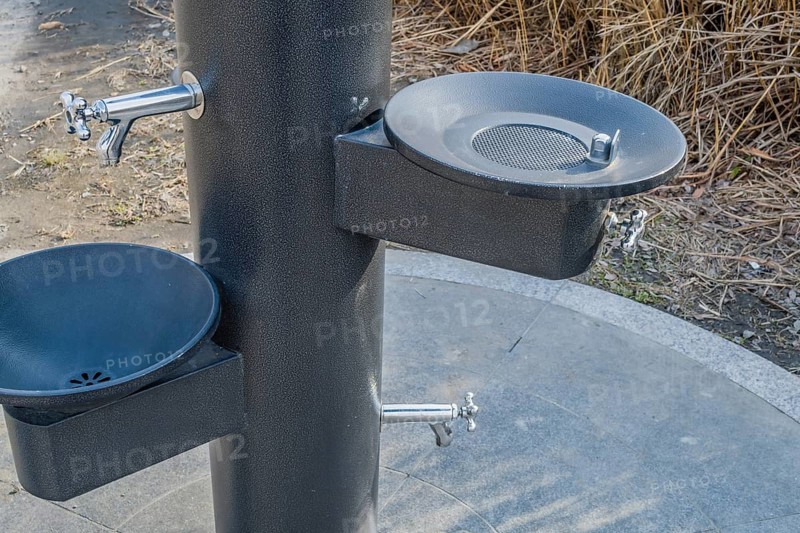 Black metal water drinking fountains near walkway in a public park in South Korea