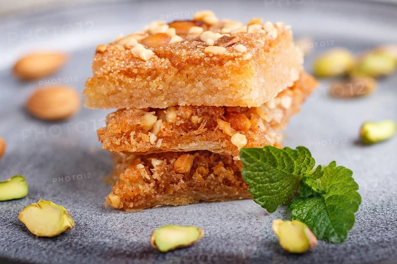 Traditional arabic sweets in gray ceramic plate on a gray concrete background. side view, close up, selective focus