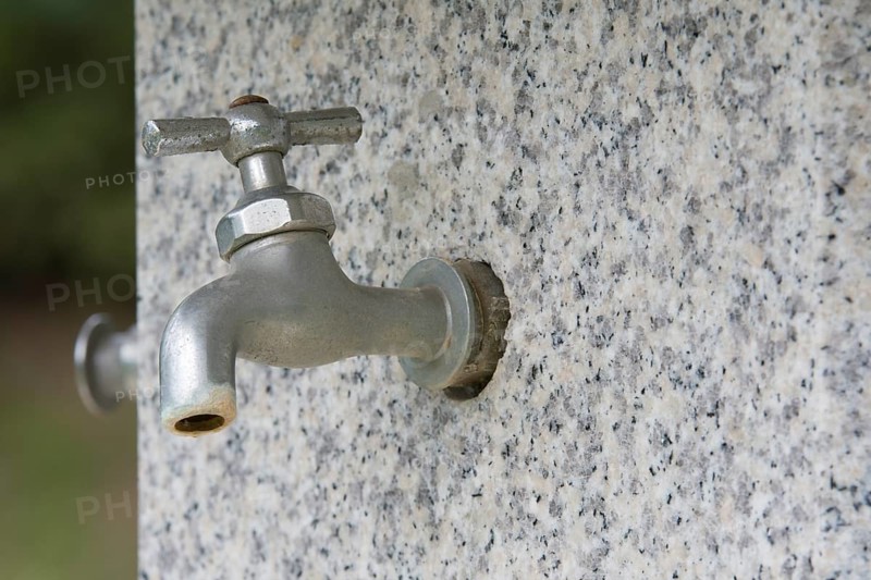 Closeup of water faucet on marble water fountain in public park in South Korea