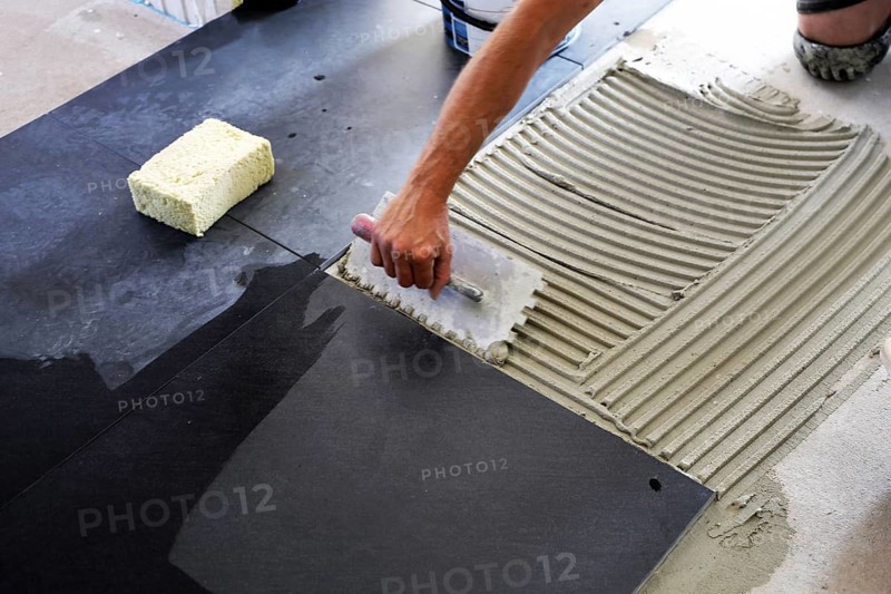 Tiler lays modern large floor tiles in a bathroom