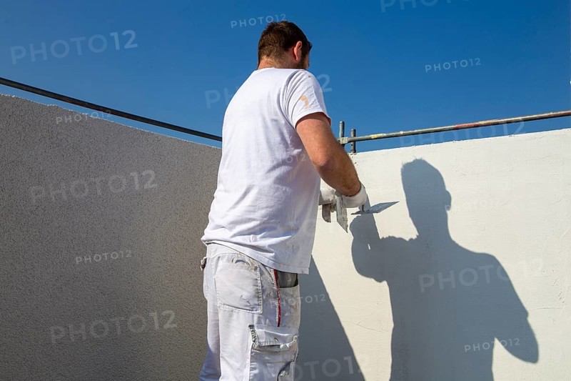 Plasterer plasters the facade of a new building