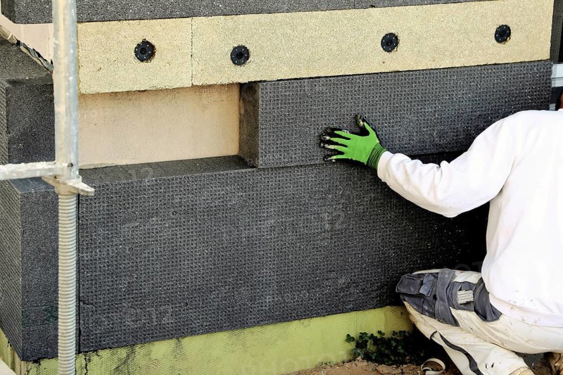 Construction workers insulate a house facade