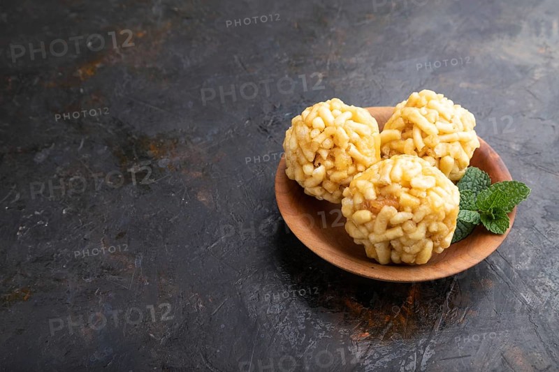Traditional Tatar candy chak-chak made of dough and honey in wooden plate on a black concrete background. Side view, copy space