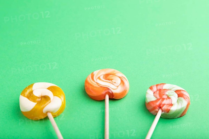 Three lollipop candies on green pastel background. copy space, top view, flat lay