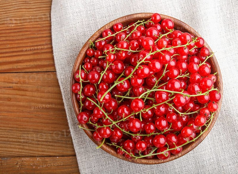 Fresh red currant in wooden bowl on wooden background. top view, flat lay, close up