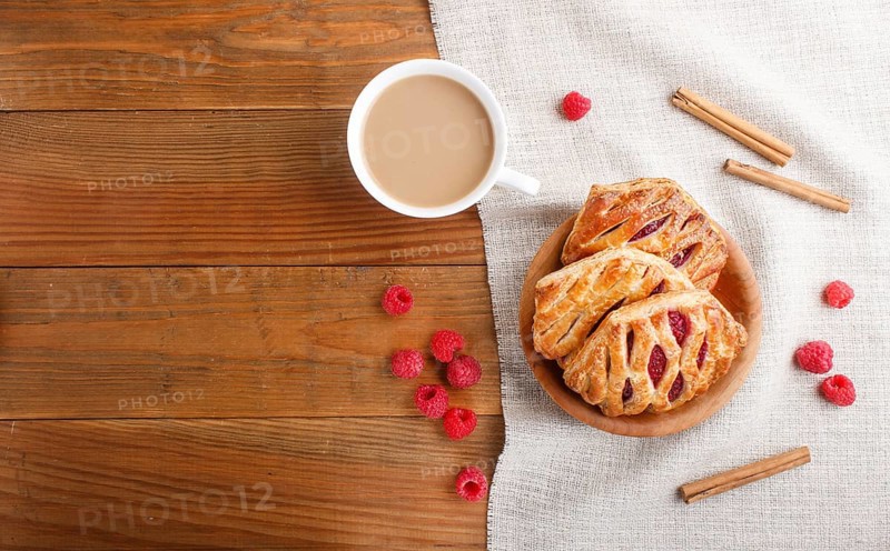 Puff pastry buns with strawberry jam on wooden background with linen textile and a cup of coffee. top view, flat lay, copy space