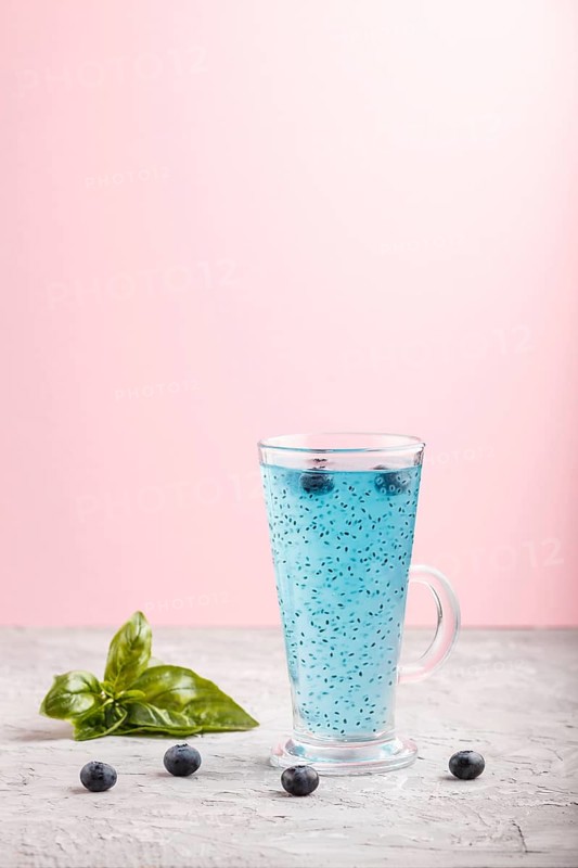 Glass of blueberry blue colored drink with basil seeds on a gray and pink background. Morninig, spring, healthy drink concept. Side view, copy space