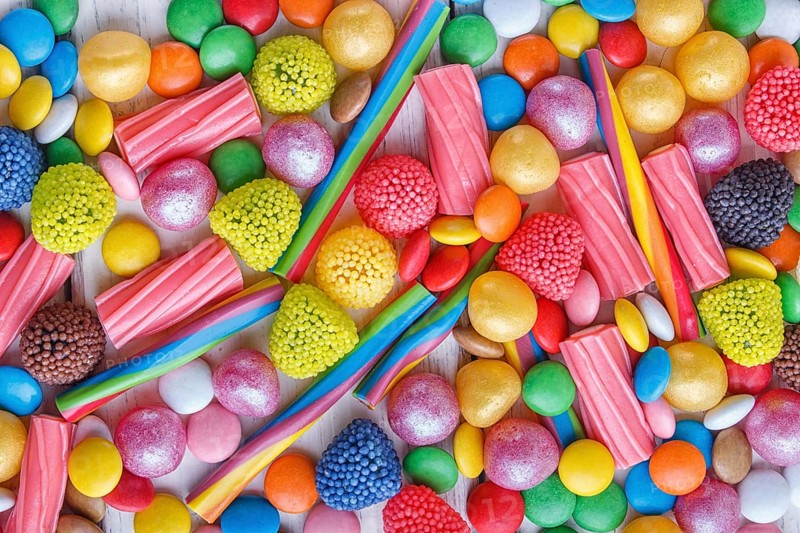 Mixed multicolored candies on white wooden background. top view, flat lay