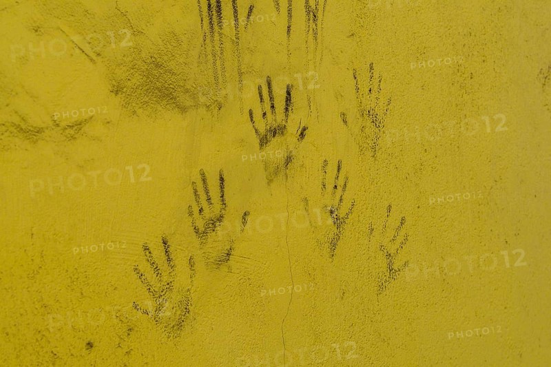 Black hand prints on side of cracked yellow wall in South Korea