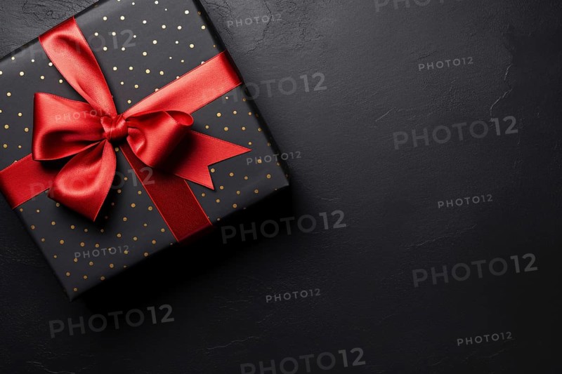 Top view of black gift box with golden dots and red ribbon. KI generiert, generiert AI generated