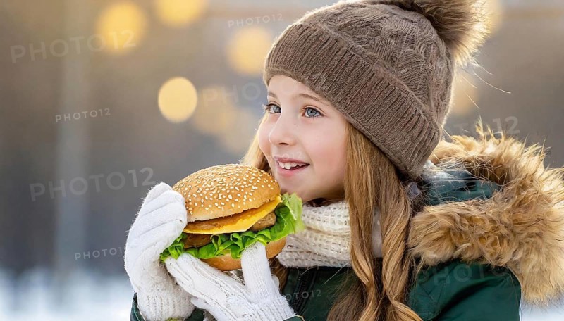 AI generated, human, humans, person, persons, child, children, girl, 10, 12, years, one person, outdoor, ice, snow, winter, seasons, eats, eating, burger, hamburger, cap, bobble hat, gloves, winter jacket, cold, coldness