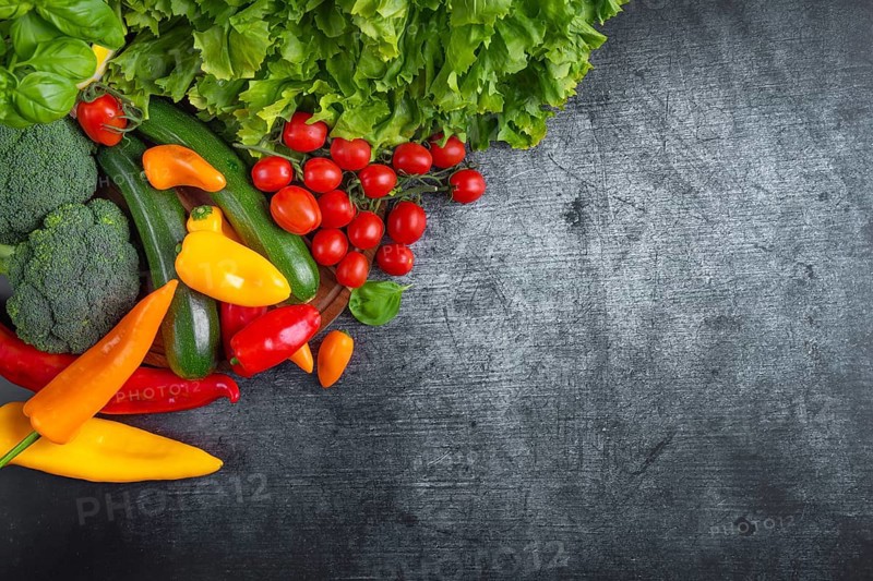Fresh lettuce, courgettes, broccoli, tomatoes and peppers arranged on a wooden board symbolises health