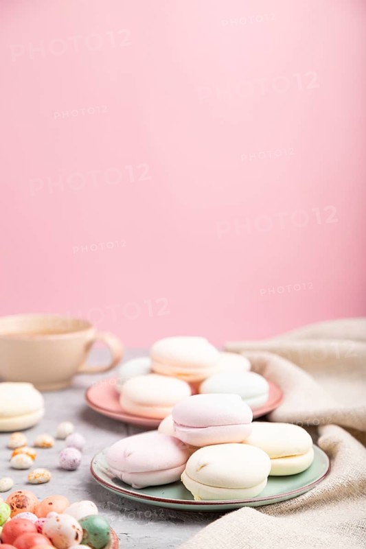 Colored zephyr or marshmallow with cup of coffee and dragees on a gray and pink background and linen textile. Side view, close up, selective focus, copy space
